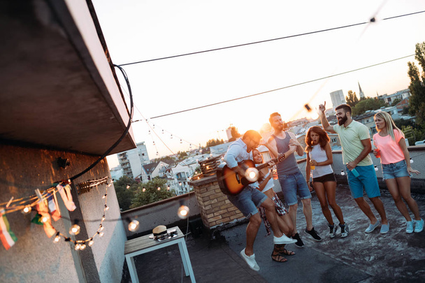 Group of happy young friends having party on rooftop - Foto, Imagem