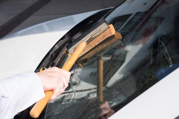 Mulher limpa o pára-brisas de seu carro
 - Foto, Imagem