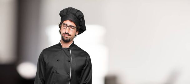 young man chef looking unenthusiastic and bored, listening to something dull and tedious and feeling like bearing a drag. - Foto, Bild