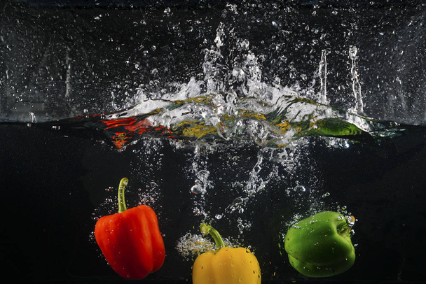 several coloured paprika falling into water splash with many bubble - Photo, Image