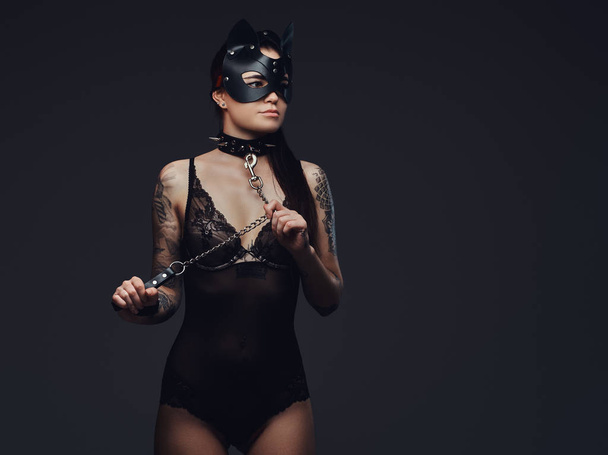 Bdsm macska bőr maszk és kiegészítők pózol a sötét háttér előtt fekete fehérnemű fárasztó szexi nő.  - Fotó, kép