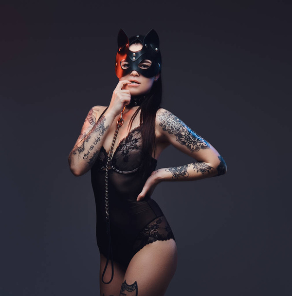Seksowny kobieta nosi czarny Bielizna Bdsm kot skórzane maski i akcesoria pozowanie na ciemnym tle.  - Zdjęcie, obraz