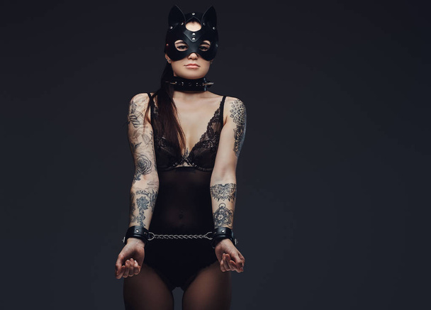 Menottée chaude brune maîtresse fille portant de la lingerie noire en cuir de chat BDSM masque et accessoires menottés
. - Photo, image