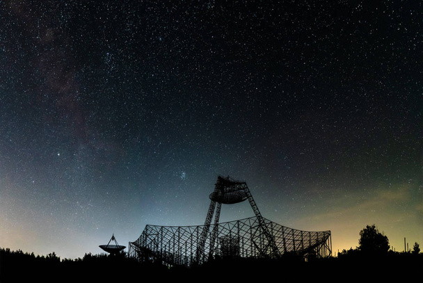 De groep van de antennes van het station van exploratie van een ionosfeer. Een silhouet tegen de achtergrond van de nachtelijke hemel met gloed en sterren. - Foto, afbeelding