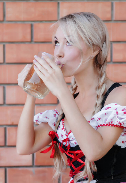Schöne Frau trinkt Bier im Oktoberfestkleid.  - Foto, Bild