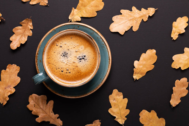 Autumn composition. Cup of coffee and dry leaves on black background. Top view. Flat lay. - 写真・画像