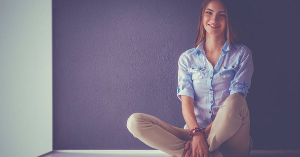Young woman sitting on the floor near dark wall - Foto, immagini