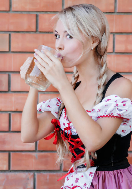Beautiful woman drinks beer on Octoberfest.  - Photo, Image