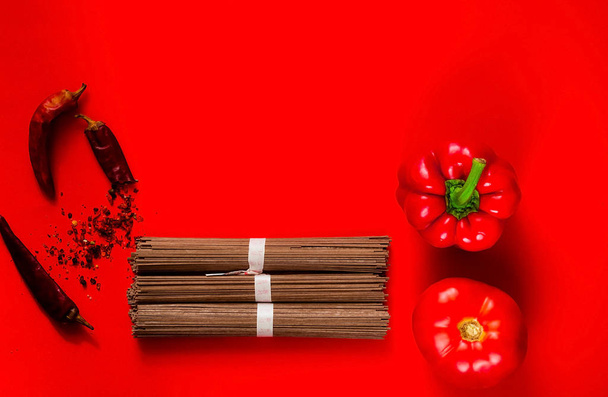 traditional  japanese soba noodles and ingredients on creative red background, concept of   asian food and healthy diet,  copy space, closeup - Photo, Image