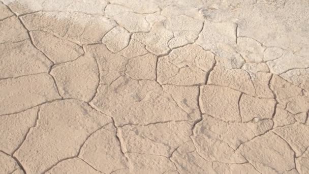 Nahaufnahme: Detail des trockenen rissigen Bodens in der heißen, sonnigen Wüste. kein Leben in trockenen, geschädigten Böden aufgrund der globalen Erwärmung und des starken Klimawandels. - Filmmaterial, Video