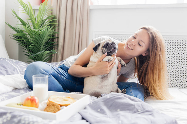 Young woman with her dog in a bed. Breakfast in bed - Foto, Bild