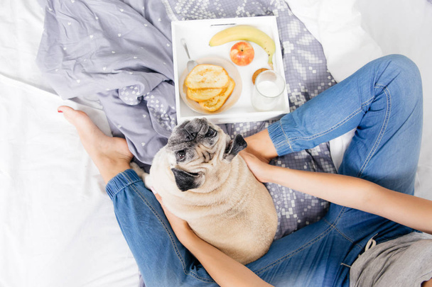 Young woman with her dog in a bed. Breakfast in bed - Valokuva, kuva