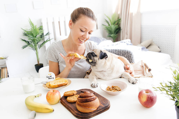 Young woman with her dog in a bed. Breakfast in bed - Fotoğraf, Görsel