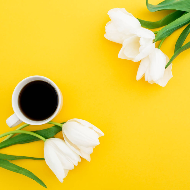 Pastel samenstelling met tulp bloemen met mok koffie op gele achtergrond, bovenaanzicht. - Foto, afbeelding