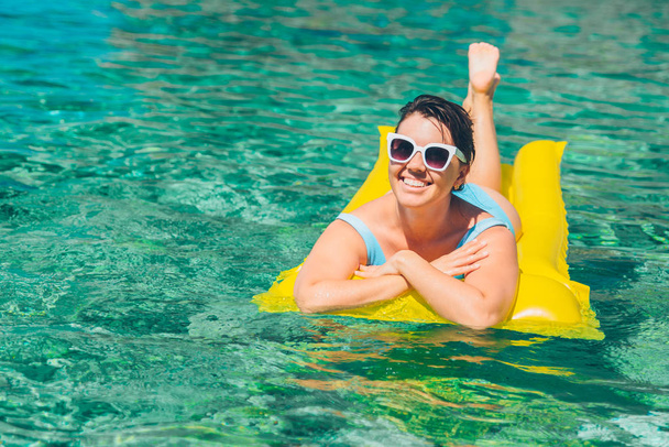 young pretty woman at yellow inflatable mattress. summer vacation - Foto, Imagem