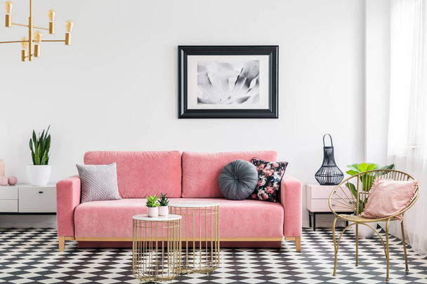 Glamor living room interior with a pink sofa, golden armchair and tables, poster and checkered tiles. Real photo - Zdjęcie, obraz