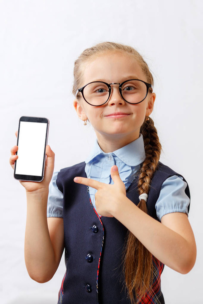 glückliches kleines Mädchen zeigt ihr Smartphone mit weißem Bildschirm. Attrappe - Foto, Bild