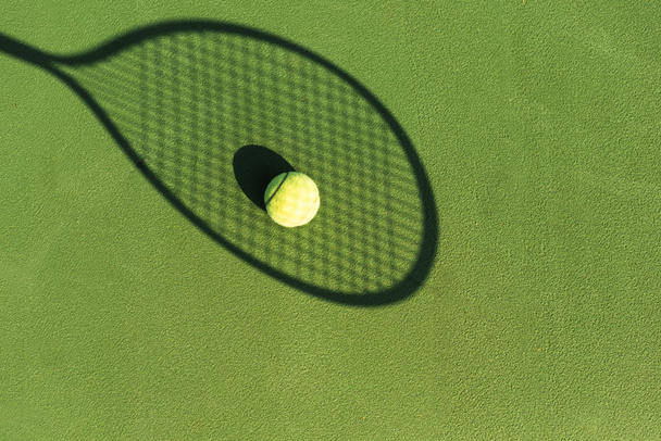 Tenis topu ve yeşil tenis kortunda tenis raketi gölge üstten görünüm - Fotoğraf, Görsel