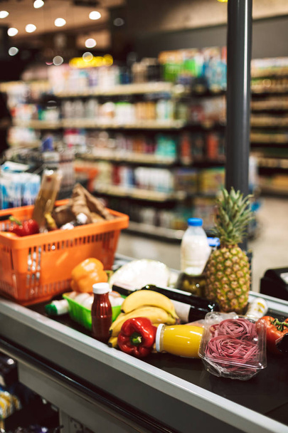 Lähikuva ostoskori ja tuotteita kassalla työpöytä moderni supermarket
 - Valokuva, kuva