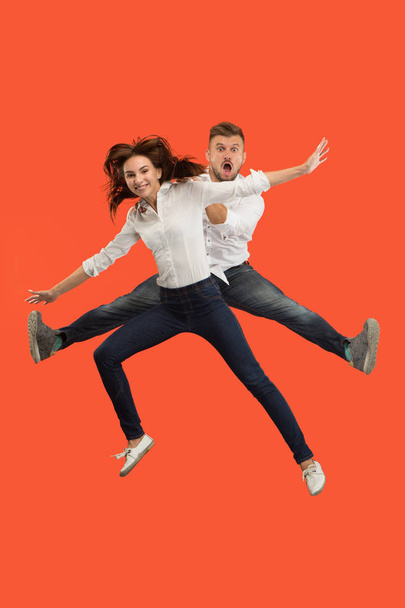 Freedom in moving. Pretty young couple jumping against red background - Foto, Bild