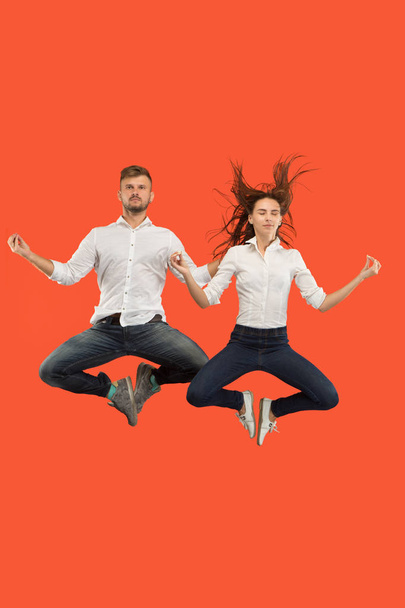 Freedom in moving. Pretty young couple jumping against red background - Фото, зображення