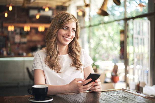 young blonde woman sitting in cafe and using smartphone - Photo, image
