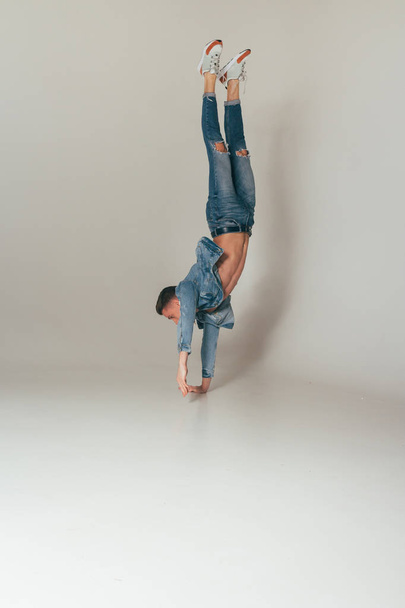 shot of jump feet up, jump, stand on one's hands, of mad, crazy, cheerful, successful, lucky guy in casual outfit, jeans, jumping with hands up, triumphant, gesturing against white background, sport - Foto, afbeelding