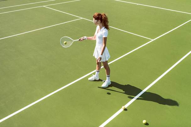 vue latérale de jeune femme attrayante en uniforme de tennis blanc jouant au tennis sur le court
 - Photo, image