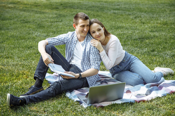 Cheerful man and woman resting in nature after learning. - Foto, afbeelding
