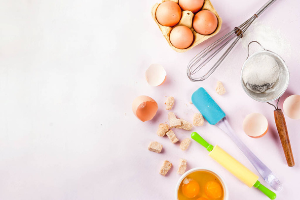 Ingredienti e utensili per cucinare uova, farina, zucchero, frusta, mattarello, su sfondo rosa chiaro, copia spazio vista dall'alto
 - Foto, immagini