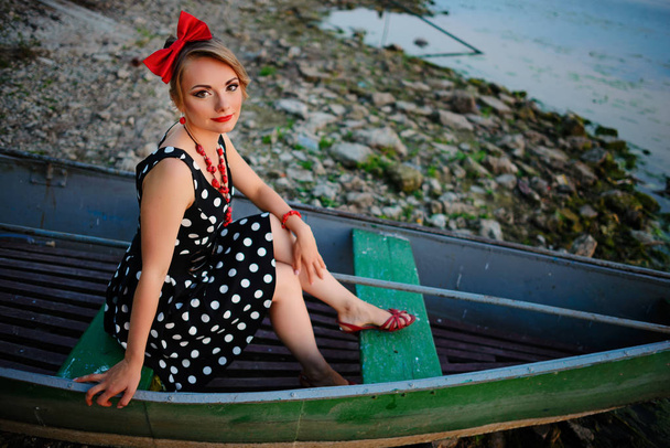 Mulher bonita vestida em um barco em uma margem do lago
. - Foto, Imagem