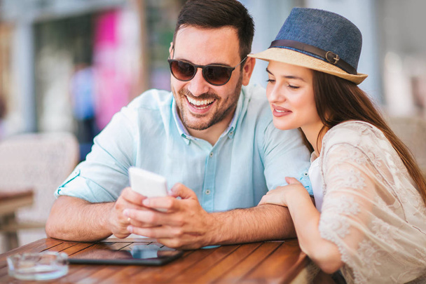 felice coppia innamorata utilizzando smartphone mentre seduto caffè
  - Foto, immagini