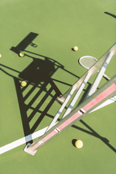 zblízka pohled kovových rozhodčí židle, tenisové rakety a míče na zelený tenisový kurt - Fotografie, Obrázek