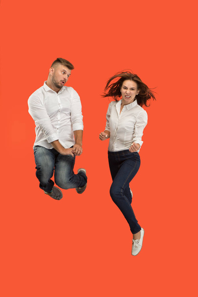 Freedom in moving. young couple jumping against red background - Photo, image