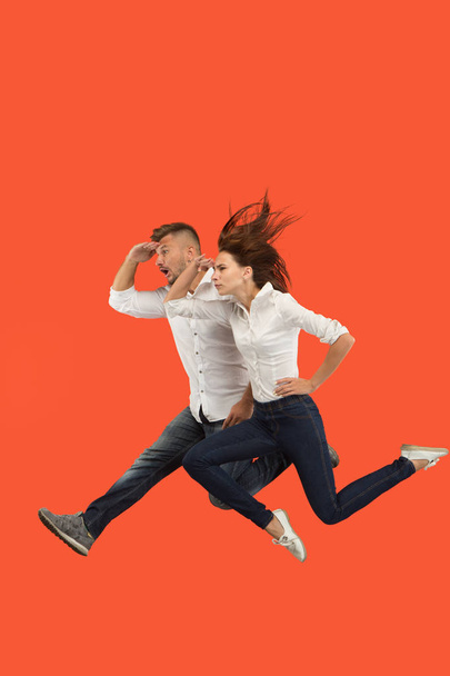 Freedom in moving. Pretty young couple jumping against red background - Fotó, kép