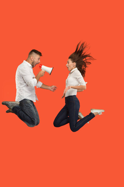 schönes junges Paar springt mit Megafon isoliert über rotem Hintergrund - Foto, Bild