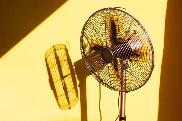 Vintage fan en zijn schaduw van zonlicht door het raam. - Foto, afbeelding