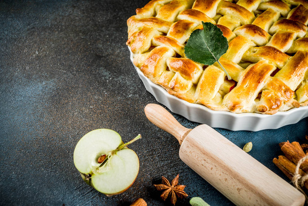 Hagyományos őszi sütés, házi almás pite fahéjas, sötét kék háttérben gördülő roll, por cukorral, friss alma, fűszerek, másolás hely felülnézet - Fotó, kép