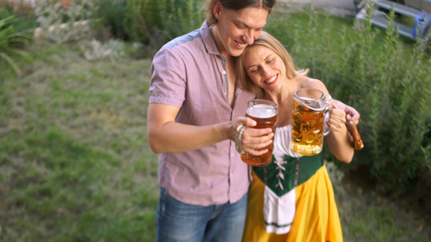 Um par de jovens no festival Oktoberfest bebem cerveja de copos grandes. A menina está vestida com um traje nacional da Baviera
 - Filmagem, Vídeo