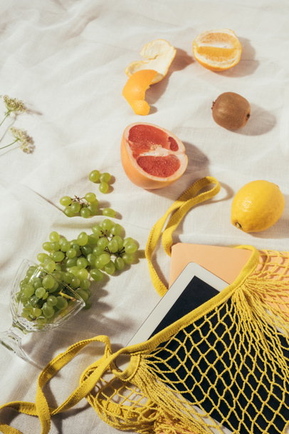 top view of string bag with digital tablet and fresh ripe fruits - Foto, imagen