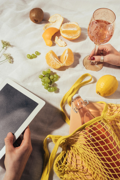 plano recortado de manos humanas con vidrio, tableta digital y bolsa de cuerda con frutas maduras
 - Foto, imagen