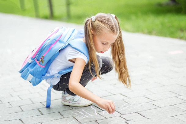 Uma criança pequena pinta giz no asfalto. O conceito de escola, estudo, educação, amizade, infância
 - Foto, Imagem