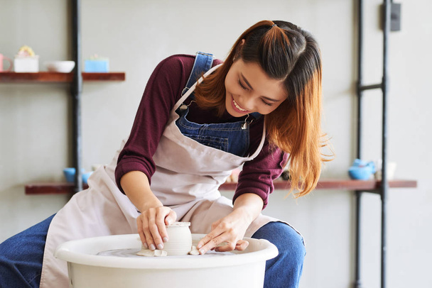 Smiling young Vietnamese woman creating clay pot - Photo, Image