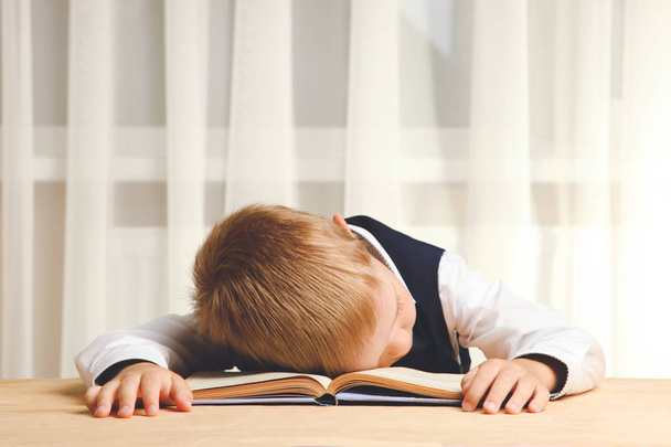 Uczniak zmęczony śpi z książki na biurku. Koncepcja szkoły. - Zdjęcie, obraz