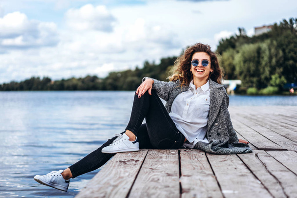 Pretty girl with curly hair relaxing near lake - Фото, изображение