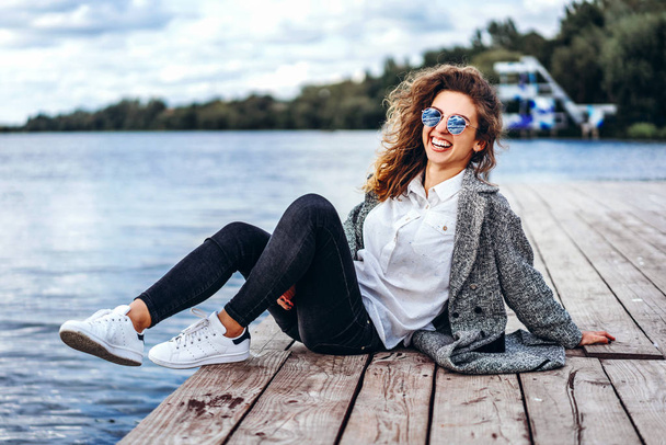 Pretty girl with curly hair relaxing near lake - Photo, image