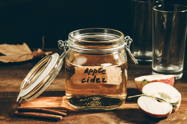 sidro di mele in vaso su un tavolo di legno su sfondo nero. Concetto bevanda alcolica
. - Foto, immagini