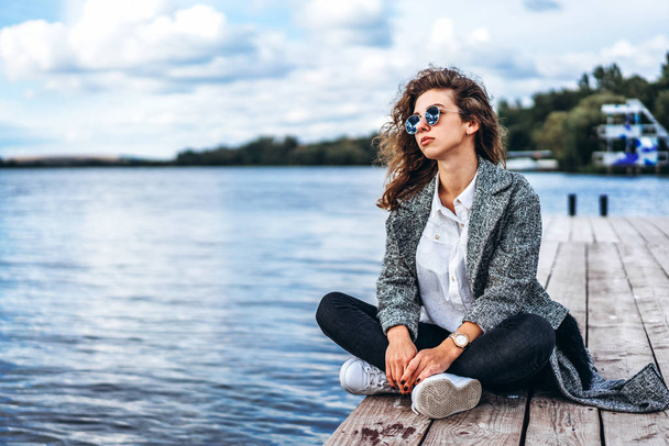 Pretty girl with curly hair relaxing near lake - Foto, imagen