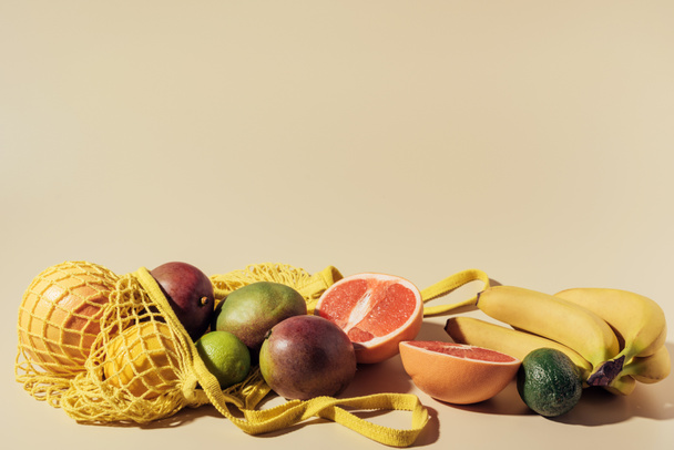 close-up view of fresh ripe tropical fruits and string bag on brown - Photo, Image