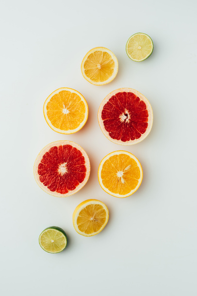 top view of grapefruit, lemon, lime and orange slices, on grey - Foto, Bild